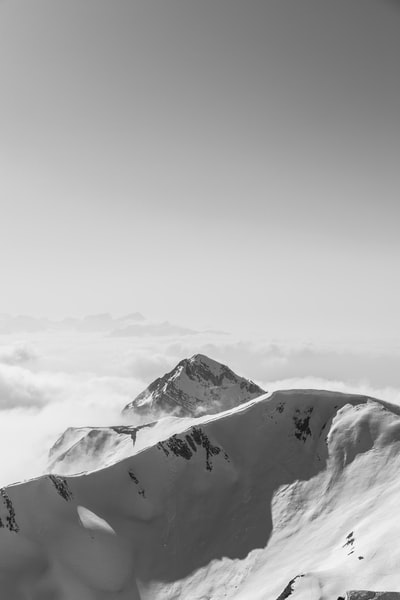 白天多云的天空下，山被雪覆盖